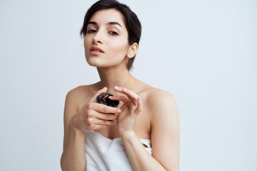 Pretty woman in white towel naked shoulders black cream in hands skin care spa procedure. High quality photo