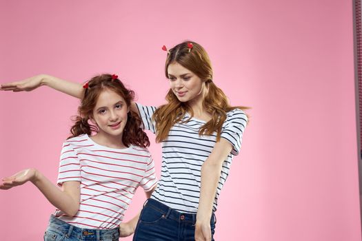 Happy sisters are having fun on a pink background and heart-shaped clothespins on their heads. High quality photo