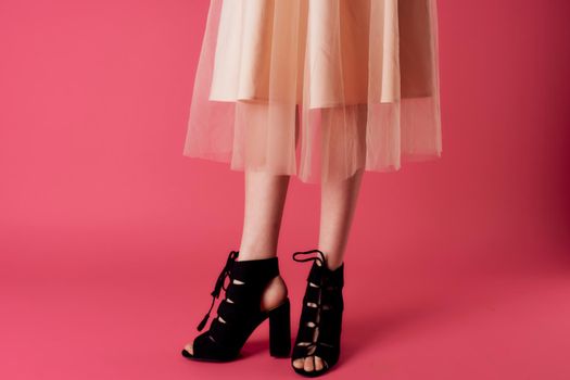 Female feet black fashionable heels shoes charm pink background. High quality photo