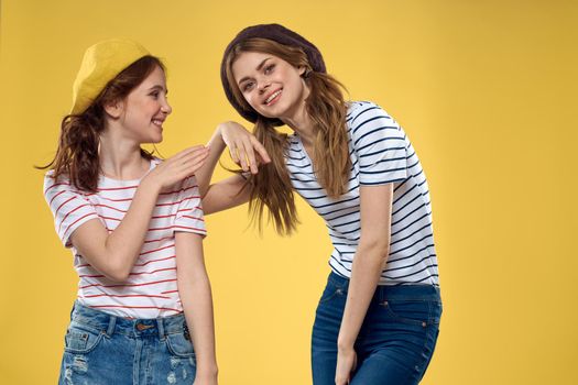 funny mom and daughter wearing hats fashion fun joy family yellow background. High quality photo