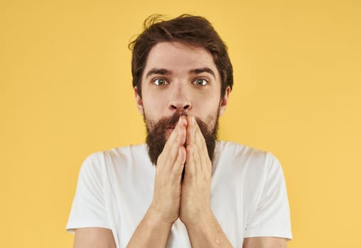 Upset man holds his hands near his face on a yellow background. High quality photo