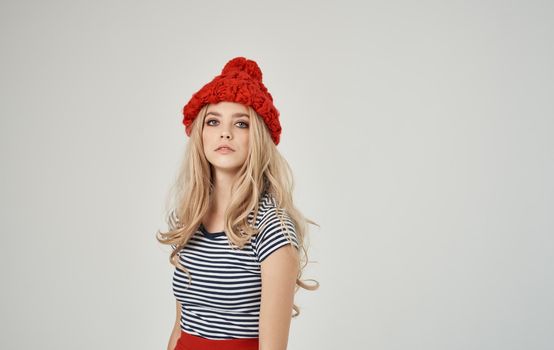 blonde woman in striped t-shirt and red hat portrait on light background cropped view. High quality photo