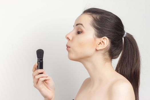 woman applying mask with makeup brush to face naked shoulders skincare. High quality photo