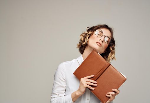 Business woman with open notebook in her hands and glasses on her face, white shirt. High quality photo