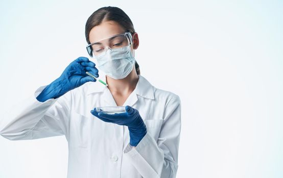 female laboratory assistant in a medical mask with a chemical element in a flask vaccination. High quality photo