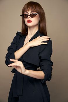 Brunette in a black coat touches his shoulder dark glasses beige isolated background