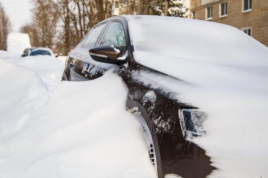 close-up view on snow-covered car at sunny winter morning with selective focus