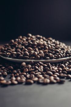 saucer with coffee beans and white cup on gray table close-up. High quality photo