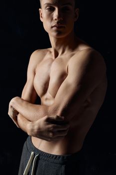 sports guy on a black background naked torso fitness gymnastics arms crossed on his chest. High quality photo