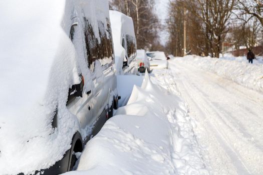 close-up view on snow-covered vehicles at sunny winter morning with selective focus