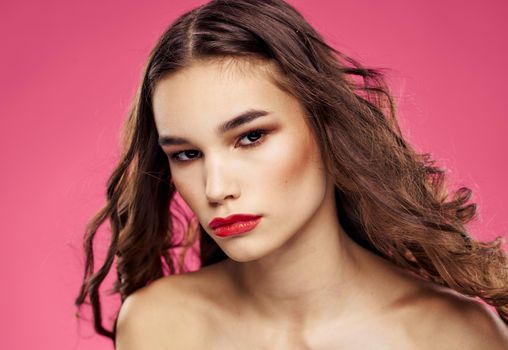 Pink background female portrait bared shoulders red lips. High quality photo