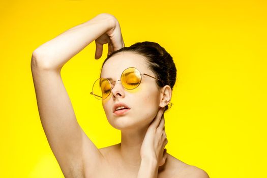 woman with bare shoulders clear skin yellow glasses hand gesture. High quality photo
