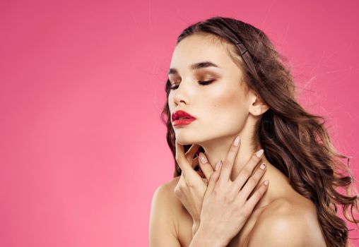 Woman with closed eyes on a pink background evening makeup red lips. High quality photo