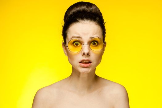 attractive woman with bare shoulders yellow glasses isolated background. High quality photo