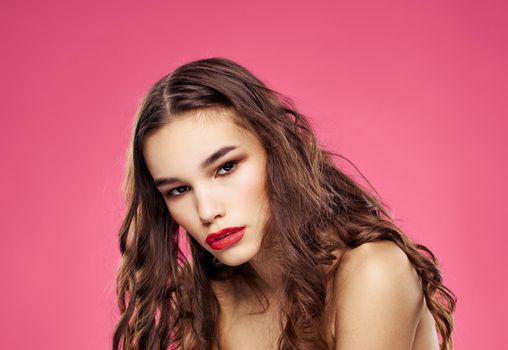Pink background female portrait bared shoulders red lips. High quality photo