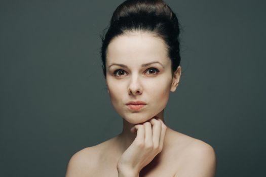 brunette with bare shoulders gathered hair hand near face. High quality photo