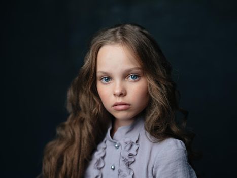 portrait of a beautiful girl in a gray dress on a dark background and curly hair blue eyes. High quality photo