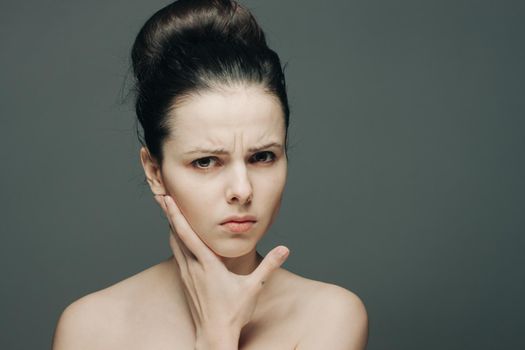 woman with bare shoulders gathered hair discontent hand on face. High quality photo