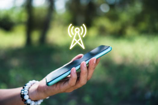 People hand using smartphone looking for signal wifi in off the grid no power space area or in the wood jungle.