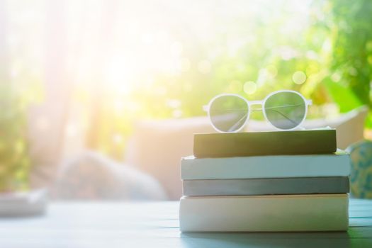 Books on table with sunglasses on top in resort room on vacation in holiday. Reading relax therapy education concept.