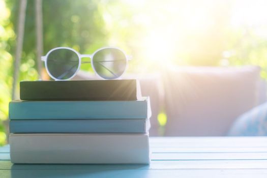 Books on table with sunglasses on top in resort room on vacation in holiday. Reading relax therapy education concept.