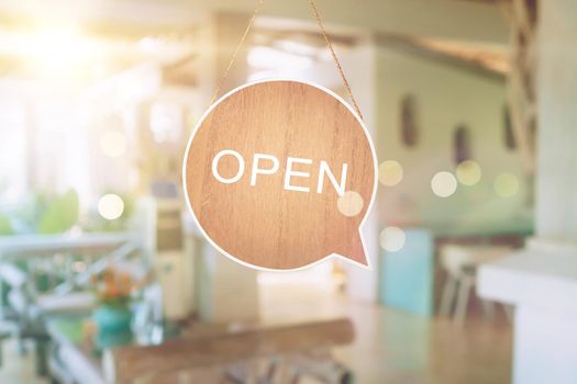 A business sign that says open on cafe or restaurant hang on door at entrance. Vintage color tone style.