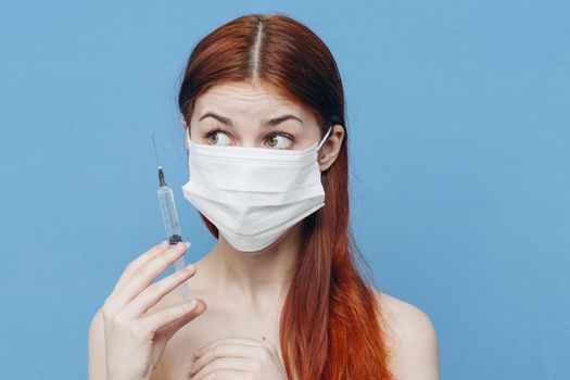 woman in medical mask holds syringe in hand and bare shoulders botox injection. High quality photo