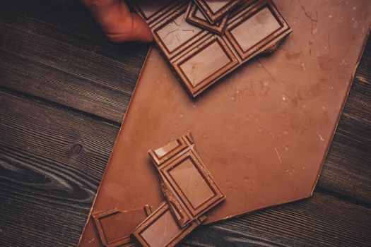broken chocolate bar diagonal cubes texture wood background. High quality photo