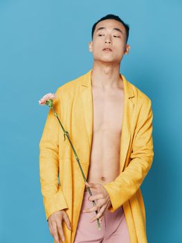 Asian guy in yellow coat holds flower in hand cropped view. High quality photo