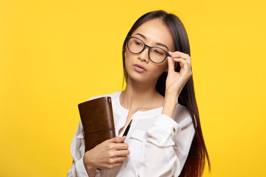 pretty brunette executive manager holding notepad yellow background. High quality photo
