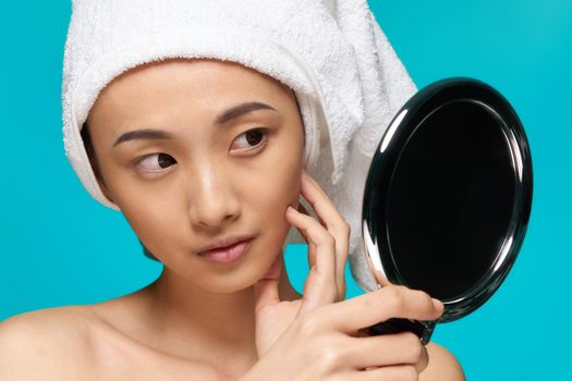 pretty woman naked shoulders towel on head mirror in hands close-up clean skin. High quality photo