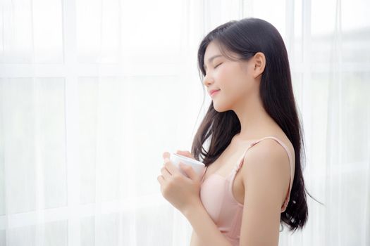 Beautiful young asian sexy woman in underwear drinking coffee near windows in the morning, girl with seductive figure fit drinking beverage for relax and resting after wake up, lifestyle concept.