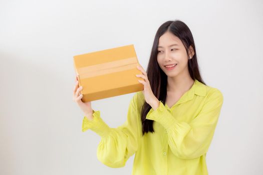 Young asian woman smiling and holding cardboard box with surprise at home, happy female carrying parcel box with excited, present and gift, packaging for deliver, online shopping store and service concept.