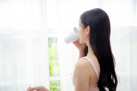 Beautiful young asian sexy woman in underwear drinking coffee near windows in the morning, girl with seductive figure fit drinking beverage for relax and resting after wake up, lifestyle concept.