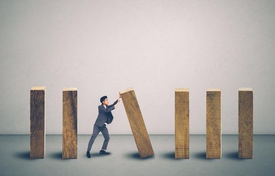 Risk of investment with economy, businessman push and stop wooden block domino with falling, management of strategy for prevention of bankruptcy, financial and insurance, crisis of business concept.