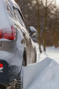 close-up view of car covered with snow and snow drift on its wheel, selective focus