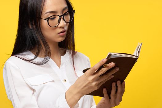 woman with a notebook in her hands in a white shirt official manager yellow background. High quality photo