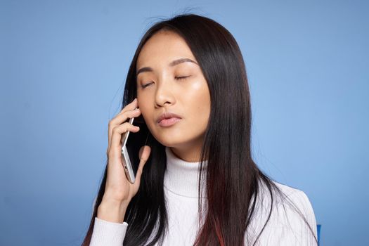 woman asian appearance talking on the phone technology studio blue background. High quality photo