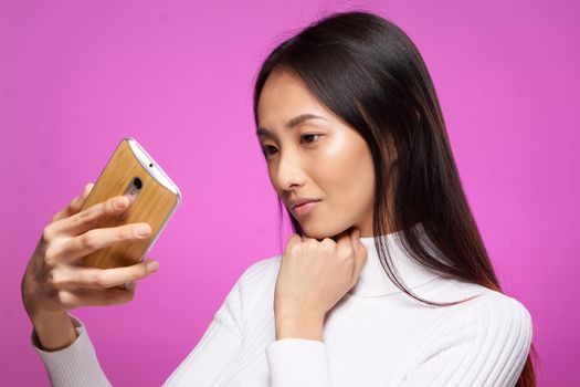 cute brunette phone in hand internet technology lifestyle pink background. High quality photo