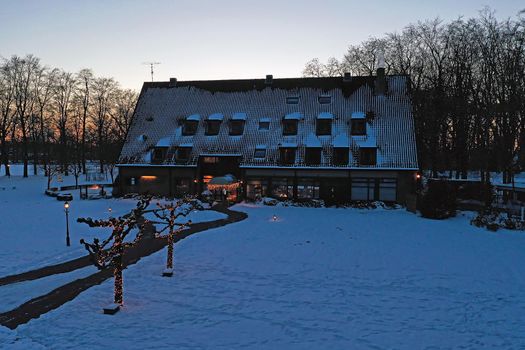 Traditional snowy farm house in winter in the countryside from the Netherlands at sunset