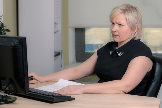 A female director working in an office is sitting at a table, analyzing business statistics, checking documents. Close-up.