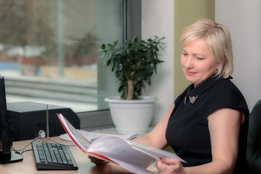 A female director working in an office is sitting at a table, analyzing business statistics, checking documents. Close-up.