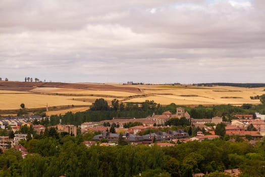 Wide-shot of a town with an old church surrounded by trees and yellow trees on a cloudy day