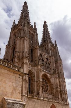 Lateral shot of Burgos' Cathedral main facade and towers against a cloudy sky