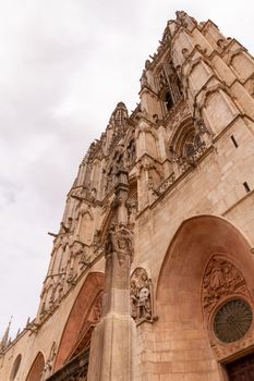 Low-angle view Burgos' Cathedral main facade and towers, with a spire in the foreground