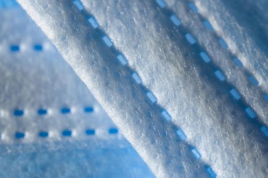 Super macro abstract close up of a 3-ply disposable face mask. Individual fibers visible along the printed paper like seam. Background with copy space