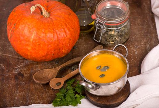 Bowl of pumpkin soup on rustic wooden background.