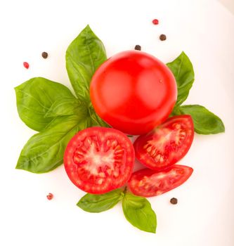 Tomatoes and basil leaves isolated on white close up.