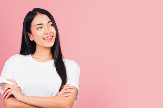 Asian happy portrait beautiful cute young woman standing her smile confidence with crossed arms isolated, studio shot on pink background and copy space, Thai female looking to side away