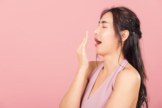 Portrait Asian beautiful young woman emotions tired and sleepy her yawning covering mouth open by hand, studio shot isolated on pink background, Thai female insomnia concept